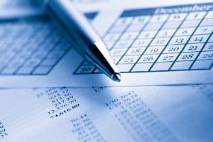 Pen resting on financial documents and calendar, symbolizing planning and staying within your budget.
