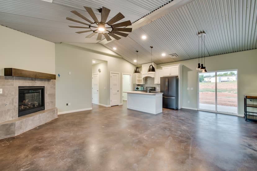 Finished barndominium interior with a vaulted corrugated metal ceiling, stained concrete floors and an open kitchen