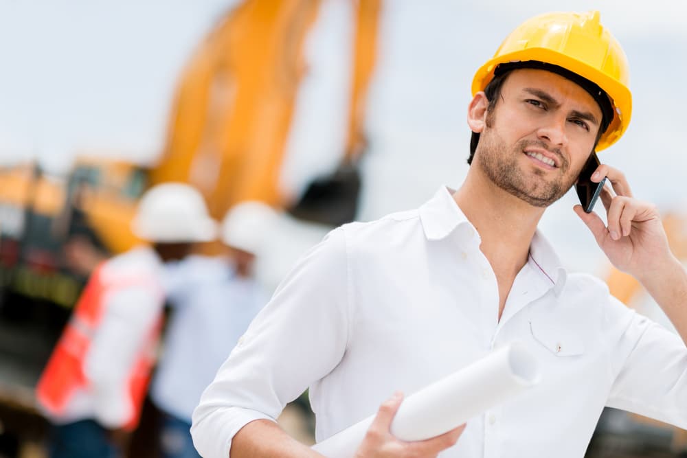 Engineer at a construction site making a business call
