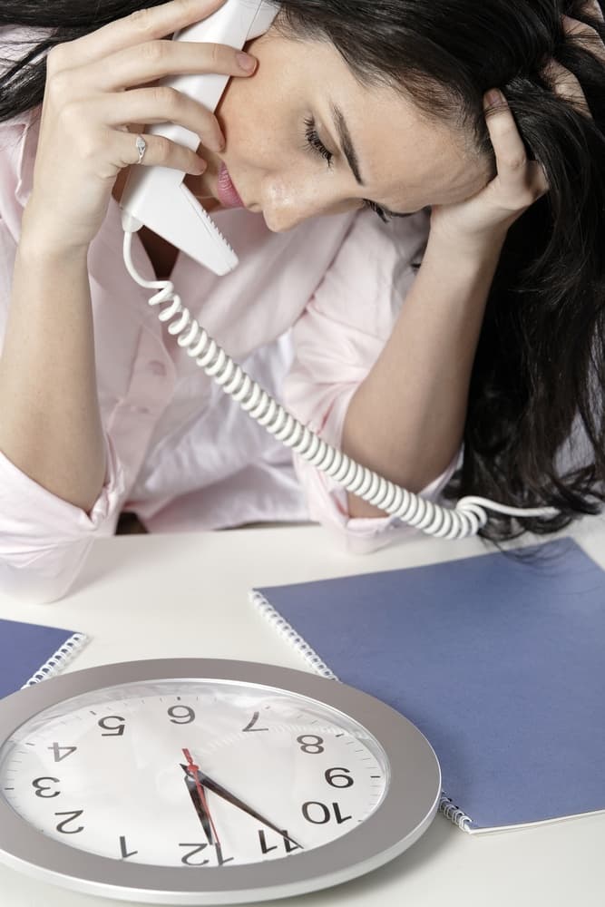 Woman on the phone watching a clock with a deadline approaching.jpeg