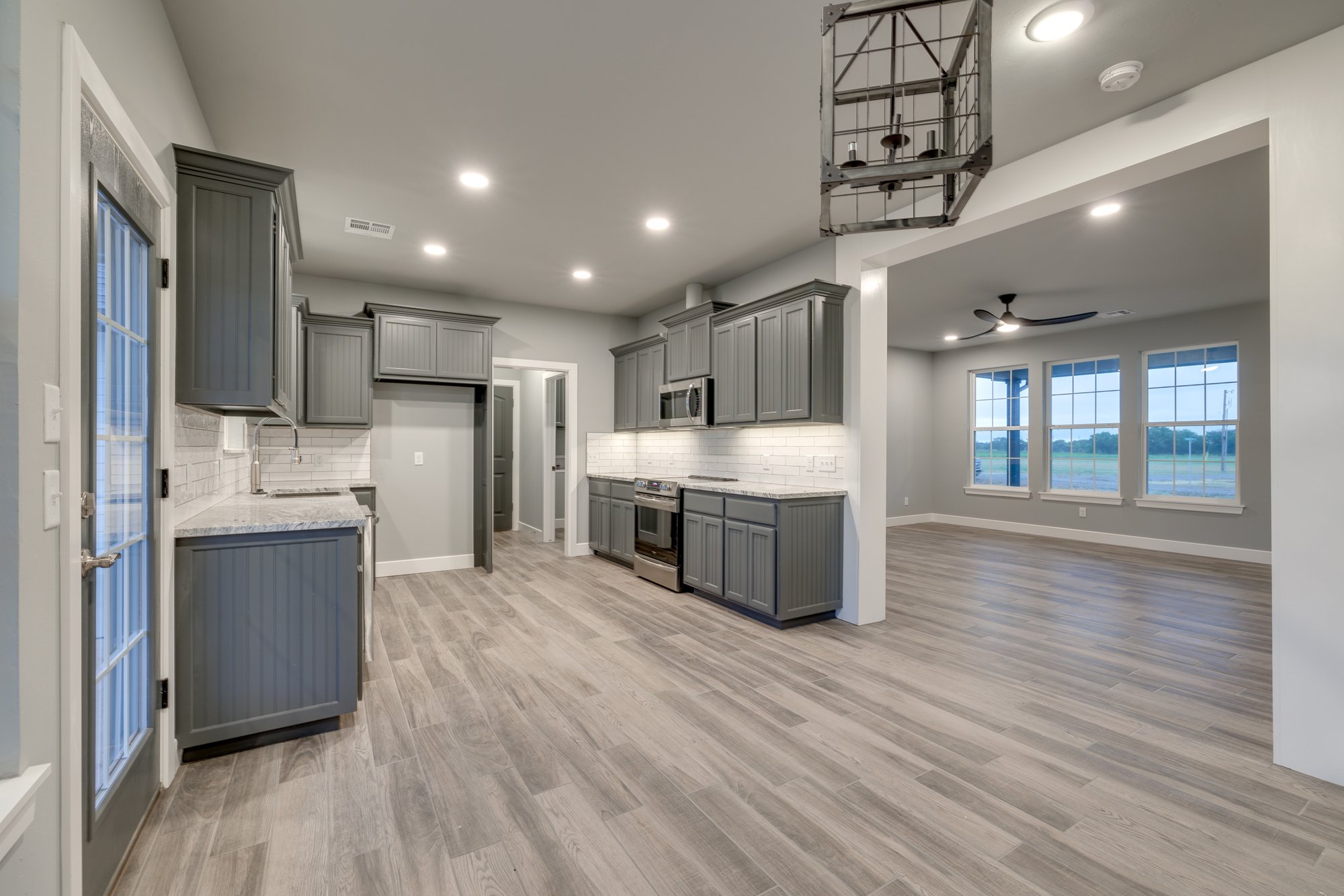 Modern kitchen with gray cabinets and open living area by Purcell Oklahoma custom home builder