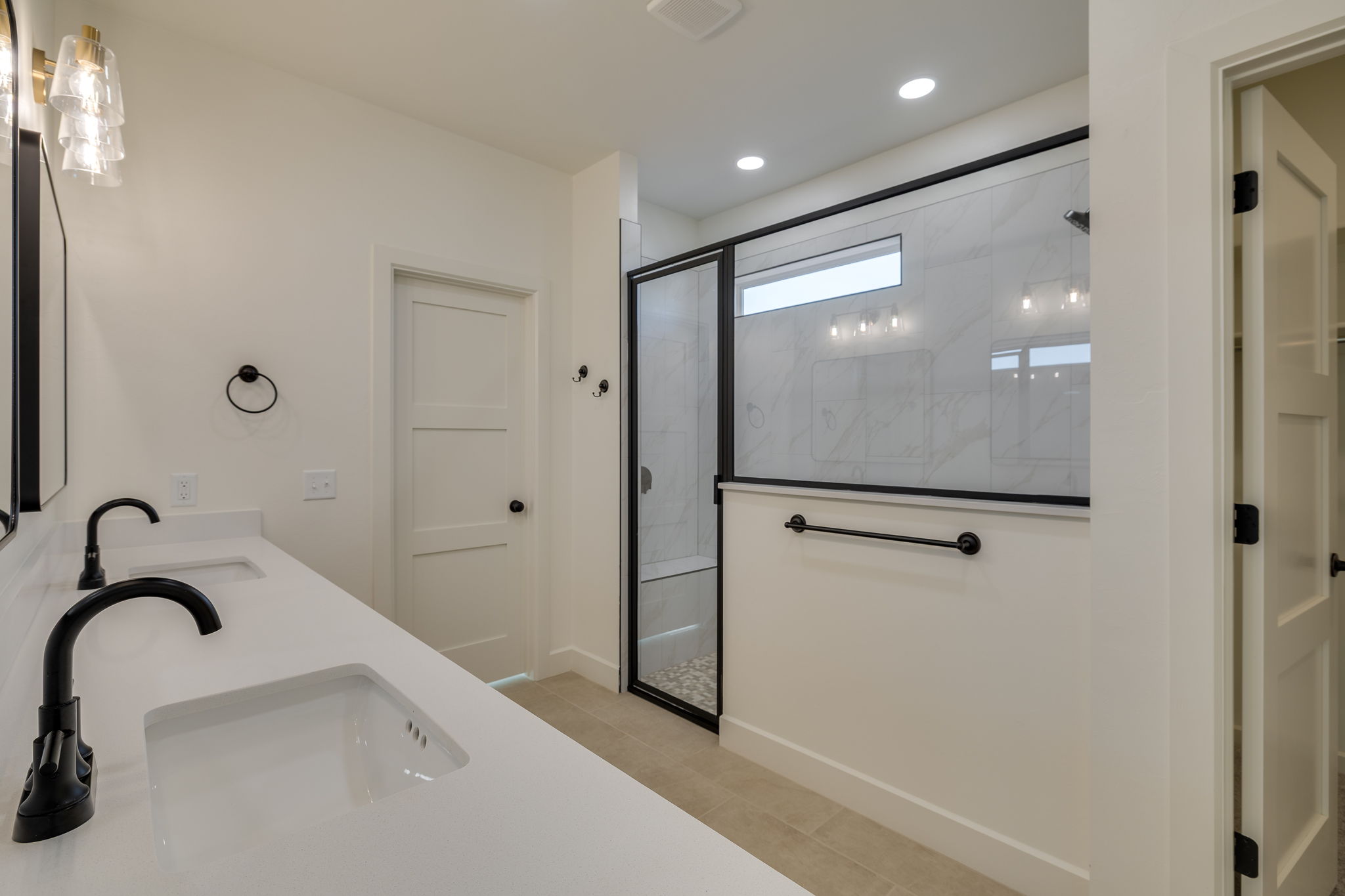 Elegant bathroom home design with dual vanities, black fixtures, and a glass-enclosed shower.