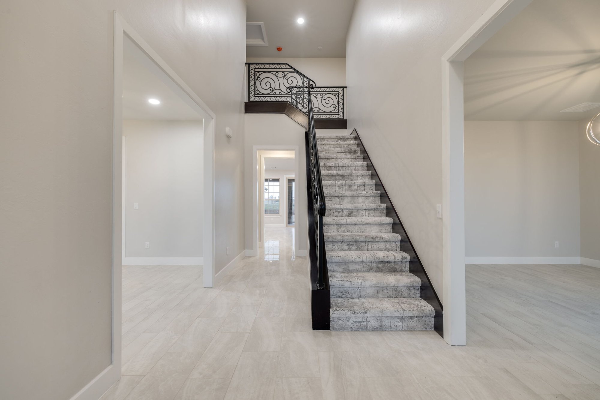 Two-story entryway in a Piedmont, Oklahoma custom home with a decorative staircase, modern chandelier, and open layout.