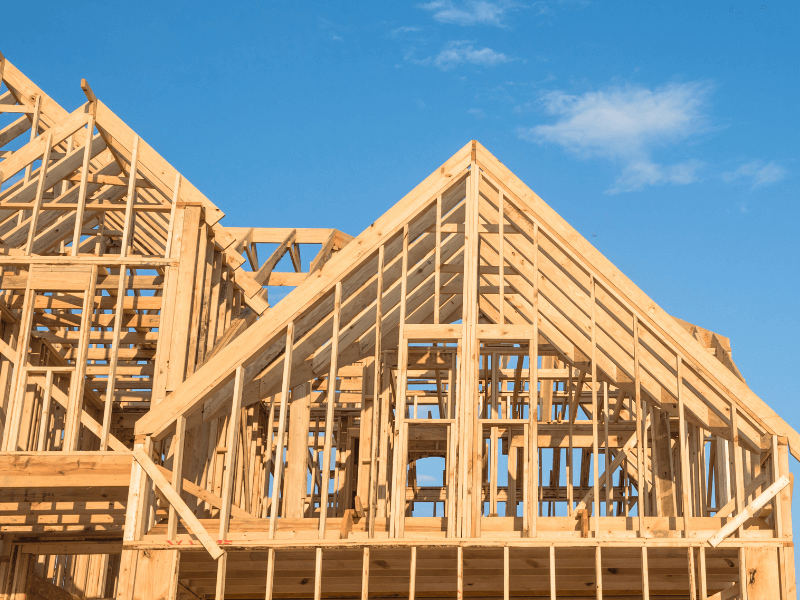 Wooden house frame under construction against a blue sky.