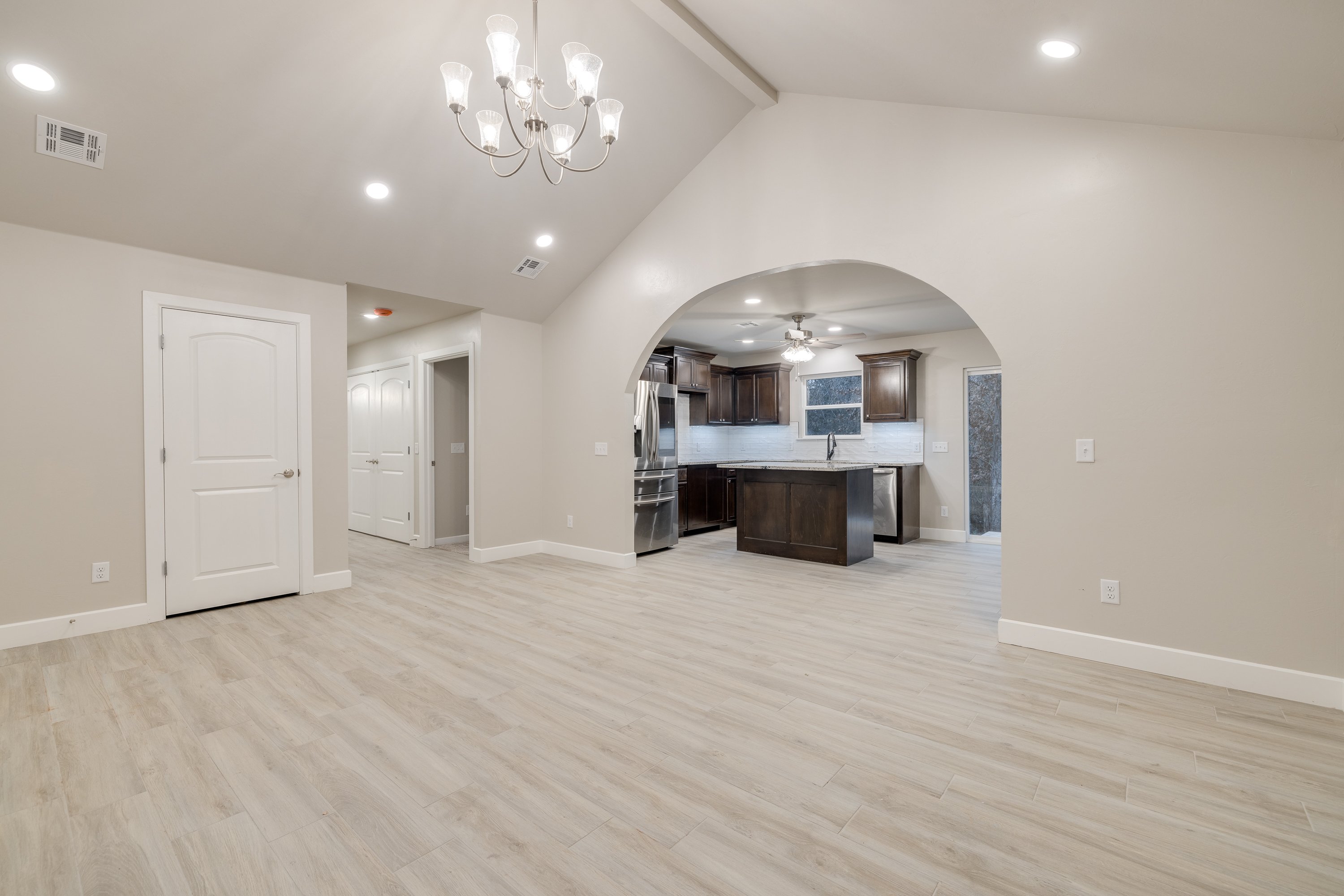 Bright dining space in modern home design with arched entryway leading to a dark wood kitchen.
