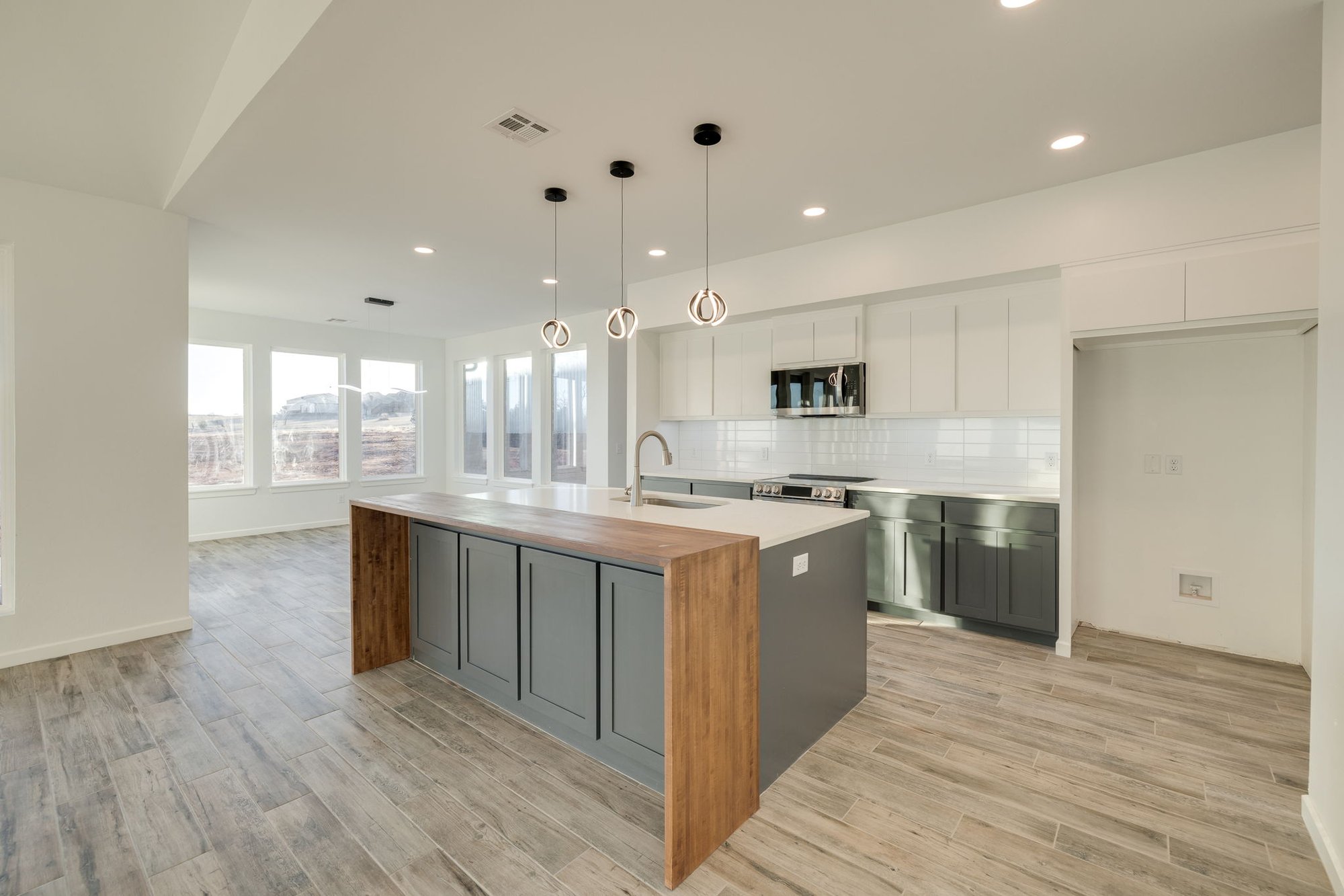 Modern kitchen in a custom-built home in Tuttle, Oklahoma with wood-accent island and pendant lighting