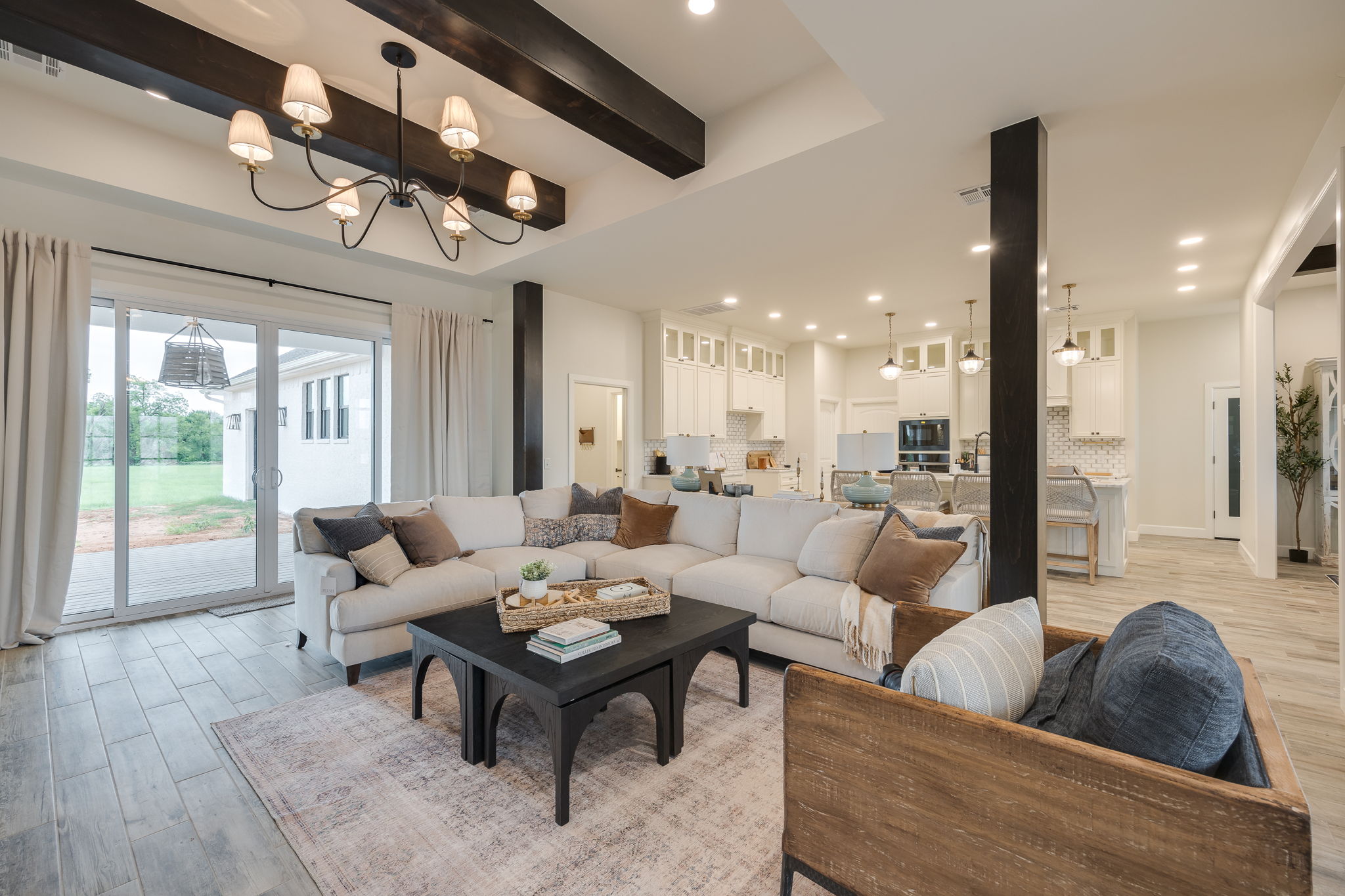 Modern open-concept living room with sectional sofa, wooden beams, and bright natural light showcasing elegant home design.