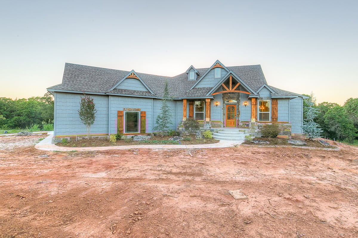 Rustic Oklahoma City home with blue shingle siding, stone accents, and natural wood trim creating a cozy craftsman-style look.