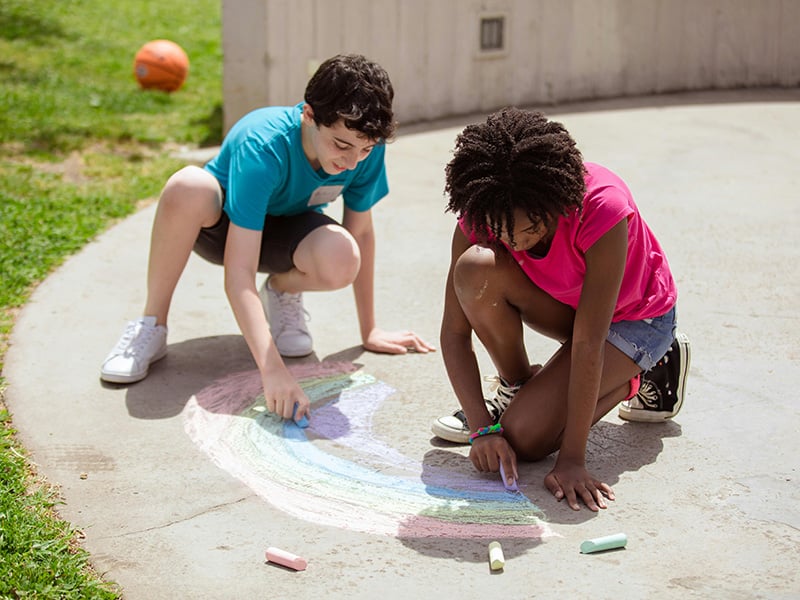 Children playing with chalk at Freedom Trail Playground in Yukon, Oklahoma, a family-friendly park with accessible features and outdoor fun.