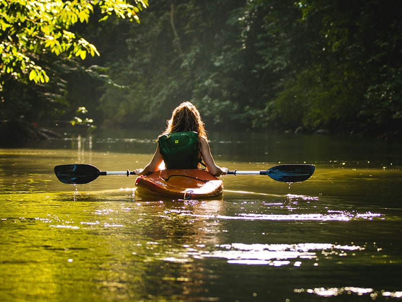 Alt text: Woman kayaking through calm waters at Stinchcomb Wildlife Refuge near Piedmont, Oklahoma, a scenic destination for outdoor recreation and wildlife watching.