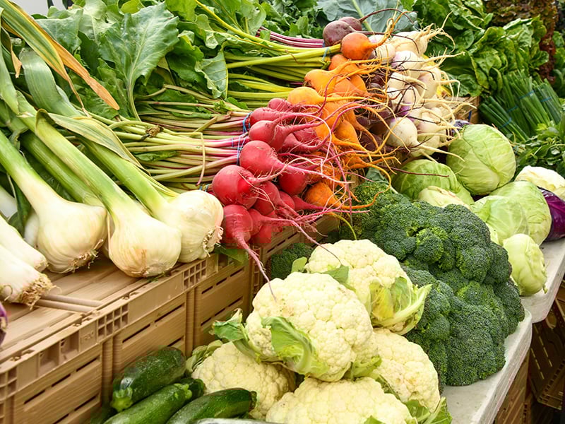 Fresh vegetables including broccoli, cauliflower, radishes, and garlic displayed at the Wildhorse Gardens & Market in Mustang, Oklahoma.